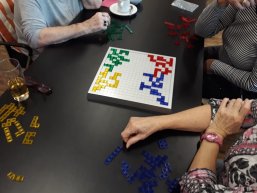 Spielsituation beim Spieletreff Ein Spiel mit farbigen Spielsteckern auf einem Tisch.