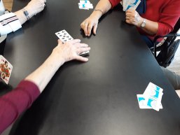 Skatrunde beim Spieltreff Man sieht Skatkarten und Hände auf einem schwarzen Tisch