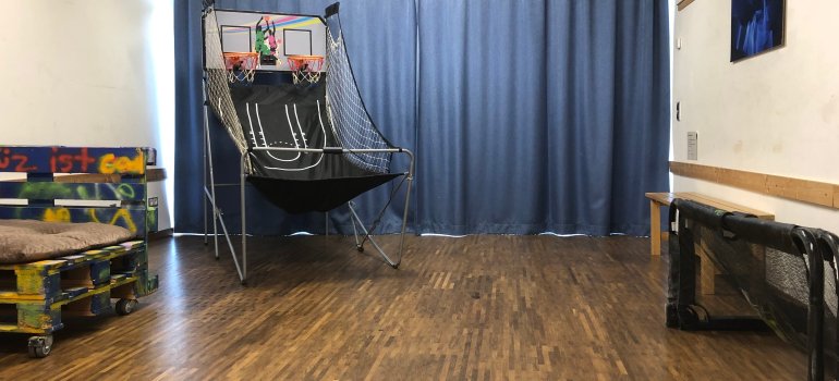 Man sieht Raum Nummer 3 des Jugendbereiches im Jugend-und Bürgerzentrum Karthause. In diesem Raum befindet sich eine Basketballmaschine, sowie Palletenbänke. 