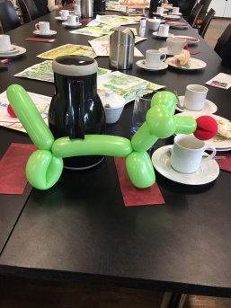 Klinikclowns beim Stadtteilfrüstück Ein grüner Luftballonhund steht auf einem gedeckten Tisch