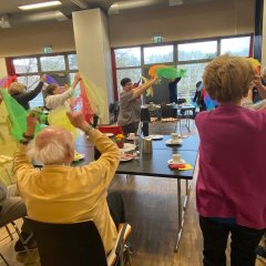 Viele Menschen in einem Saal bewegen bunte Tücher